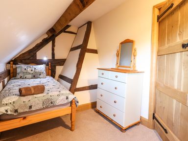 A bedroom with a single bed a wooden dresser with mirror and wooden door at The Old House in Llanidloes