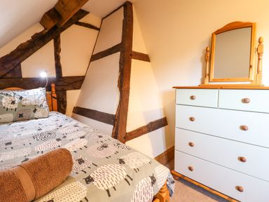 A bedroom with a bed covered with sheep printed bedding and a chest of drawers with a mirror at The Old House in Llanidloes
