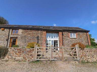 A stone building with a wooden gate at West Bowden Farm in Knowstone near South Molton