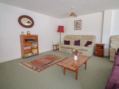 A living room with a sofa and bookshelf at West Bowden Farm in Knowstone near South Molton