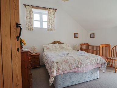 A bedroom with a bed and a baby crib at West Bowden Farm in Knowstone near South Molton