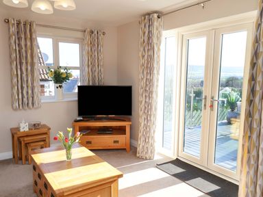 A living room with a television and sliding doors at Heather Croft in Robin Hood's Bay