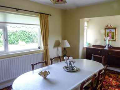 A dining room with a table set with candles chairs a lamp a sideboard and a window at Eileen's in Aughavas near Mohill County Leitrim