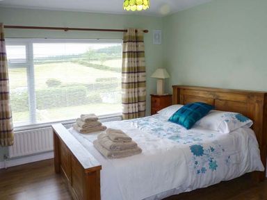 A bedroom with a wooden bed and bedside table with a lamp at Eileen's in Aughavas near Mohill County Leitrim