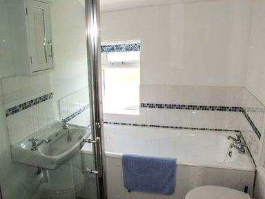 A bathroom with a sink a bathtub a blue towel and a window at Cotswold View in Clifford Chambers near Stratford-upon-Avon