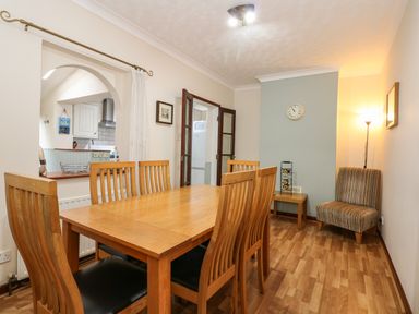 A dining room with wooden table and chairs a small striped chair and side table at 5 Melinda Cottages in East Runton near Cromer