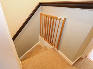 A small carpeted staircase with a wooden safety gate at 5 Melinda Cottages in East Runton near Cromer