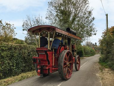 A vintage steam tractor with two people on a country road surrounded by trees and hedges at Apple Tree Cottage in Shillingstone near Sturminster Newton
