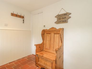 An entryway with a wooden bench, a wall-mounted coat rack with keys, and a welcome sign at Apple Tree Cottage in Shillingstone near Sturminster Newton