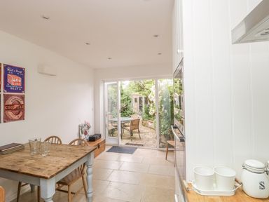A dining area with a wooden table and chairs next to glass doors leading to a garden at Apple Tree Cottage in Shillingstone near Sturminster Newton