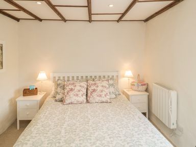 A bedroom with a bed between two nightstands each with a lamp at Apple Tree Cottage Shillingstone near Sturminster Newton