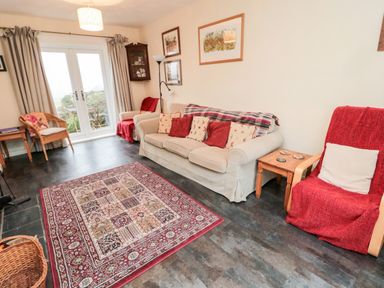 A living room with sofa armchairs rug and framed pictures on walls at Bunty's Place in Chatton near Wooler