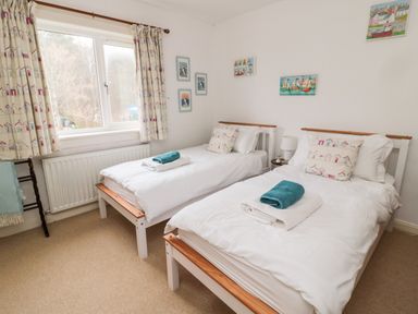 A bedroom with two single beds with white bedding and framed pictures on walls at Bunty's Place Chatton near Wooler