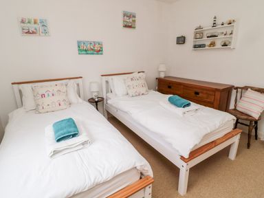 A bedroom with two single beds white bedding wooden furniture and wall decorations at Bunty's Place in Chatton near Wooler