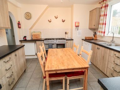 A kitchen with wooden dining table and chairs stove and utensils at Buntys Place in Chatton near Wooler