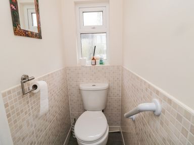 A small bathroom with a toilet a window above and a toilet paper holder on the side at Bunty's Place in Chatton near Wooler