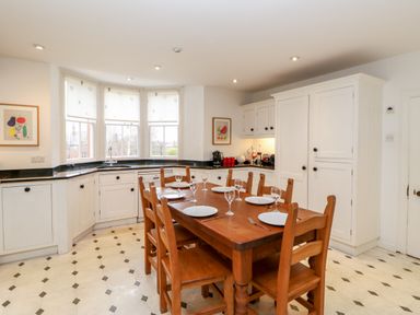 A kitchen with a wooden dining table set with plates and glasses and white cabinets at Eden House Edenhall near Penrith