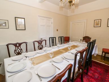 A dining room with a table set with plates glasses and cutlery surrounded by chairs at Eden House Edenhall near Penrith