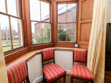 Three wooden chairs with red patterned upholstery near wooden framed windows at Eden House Edenhall near Penrith