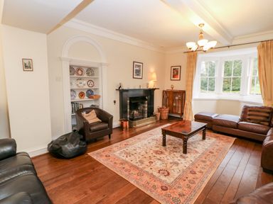 A living room with leather sofas a wooden coffee table a fireplace and a bay window at Eden House in Edenhall near Penrith