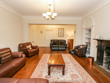 A sitting room with leather sofas a wooden coffee table a fireplace and built-in shelves at Eden House Edenhall near Penrith
