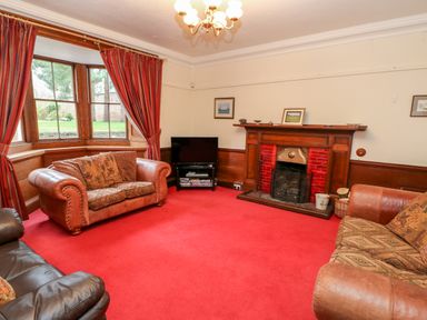 A living room with a red carpet a fireplace and leather sofas at Eden House Edenhall near Penrith