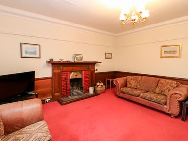 A living room with a fireplace and patterned sofas at Eden House in Edenhall near Penrith