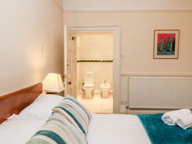 A bedroom with a bed lamp and bathroom visible through an open door at Eden House in Edenhall near Penrith