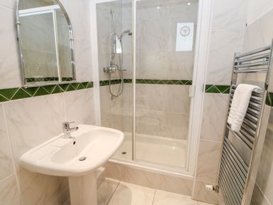 A bathroom with a shower enclosure sink mirror and towel radiator at Eden House Edenhall near Penrith