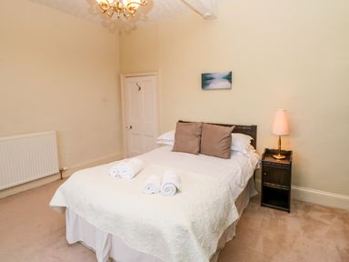 A bedroom with a double bed pillows bedside table lamp and a painting on the wall at Eden House in Edenhall near Penrith