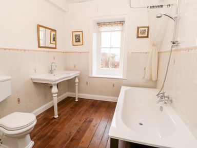 A bathroom with a bathtub shower toilet sink wooden floor and window at Eden House Edenhall near Penrith