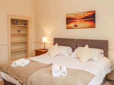 A bedroom with a double bed pillows folded towels bedside table lamp and a painting on the wall at Eden House in Edenhall near Penrith