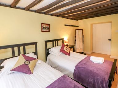 A bedroom with two single beds with purple throws and a framed picture on the wall at Eden House Edenhall near Penrith