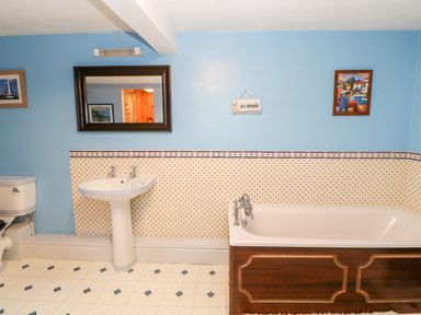 A bathroom with a bathtub a pedestal sink a toilet and a mirror on blue and patterned walls at Eden House Edenhall near Penrith