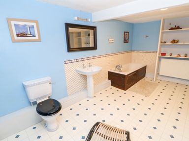 A bathroom with a toilet a pedestal sink a bathtub and shelves at Eden House Edenhall near Penrith