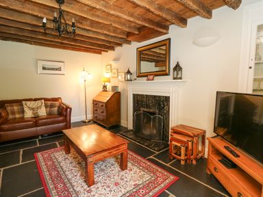 A living room with a leather sofa wooden coffee table fireplace and television at Penuwch Fach in Aberystwyth