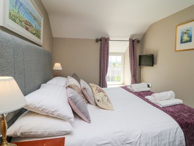 A bedroom with a bed with pillows towels and lamps and a window with curtains at Penuwch Fach in Aberystwyth