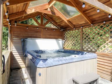 A wooden gazebo with a hot tub and a small step stool at Penuwch Fach in Aberystwyth