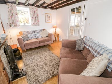 A sitting room with two sofas a rug wooden floor and a fireplace at Bron Heulog Cottage in Llangoed near Beaumaris