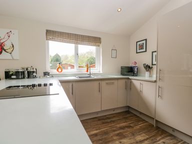 A kitchen with countertop appliances under a window with a plaid blind at Cartmel Lodge in Allithwaite near Grange-over-Sands