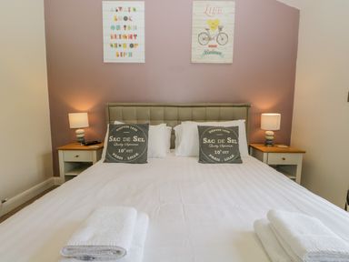 A bedroom with a double bed two bedside tables with lamps and folded towels on the bed at Cartmel Lodge in Allithwaite near Grange-over-Sands