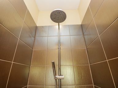 A showerhead and handheld shower in a tiled shower area at Cartmel Lodge in Allithwaite near Grange-over-Sands