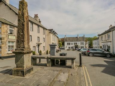 A street view with historic stone monument and buildings including Kings Arms pub in the background at Cartmel Lodge in Allithwaite near Grange-over-Sands