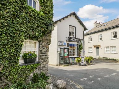 A street corner with a shop named Cartmel and buildings covered with ivy at Cartmel Lodge in Allithwaite near Grange-over-Sands