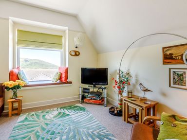 A living room with a window seat with cushions and a mountain view at Glenwood in Woolacombe