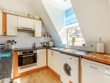 A kitchen with white cabinets a washing machine and dishwasher under the counter Glenwood Woolacombe
