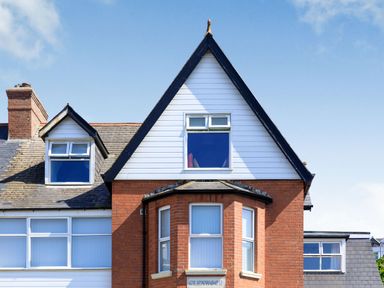 Exterior of a brick and white house with windows and a chimney at Glenwood in Woolacombe