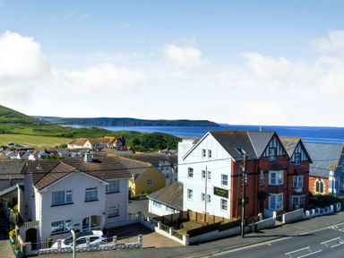 Houses near the coast with green hills and ocean in the background at Glenwood in Woolacombe