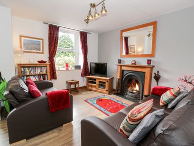 A living room with two brown sofas a fireplace and a television at Ty Gwynn in Tanygrisiau