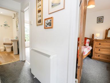 A hallway with a radiator and framed pictures between a bathroom and a bedroom at Ty Gwynn in Tanygrisiau
